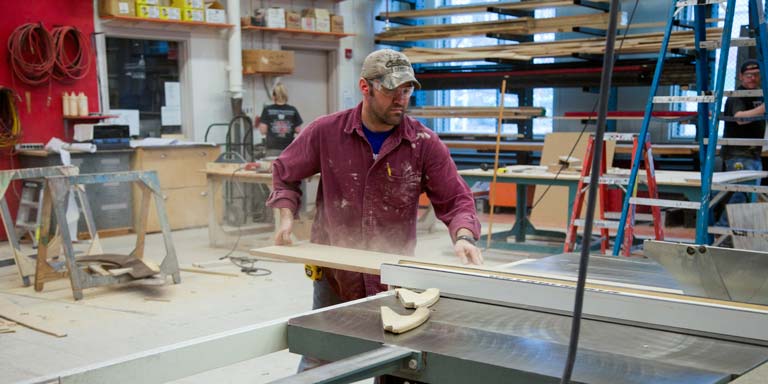 man cutting wood with saw